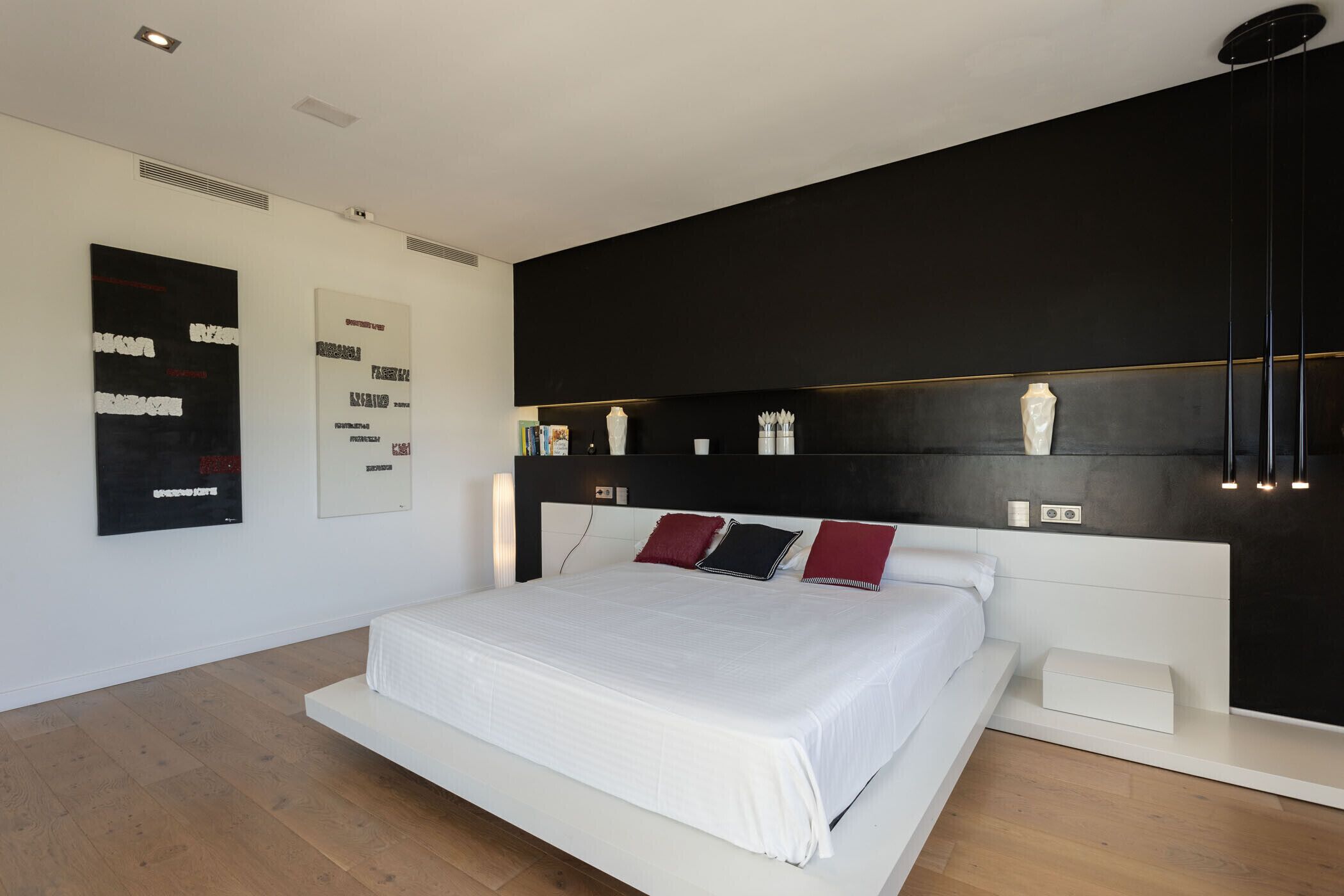 Une chambre moderne avec un grand lit, une tête de lit noire et une table de chevet blanche.