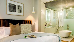A modern bedroom with a large bed, a bedside table, and a framed artwork on the wall. - Ultimate Escape in Vibrant De Waterkant at Ishani (Cape Town)