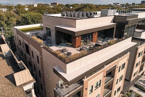 Een modern gebouw met een terras op het dak, inclusief zitplaatsen buiten en een tuin.