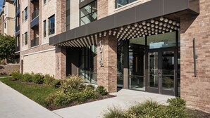 Un bâtiment moderne avec une façade en briques, de grandes fenêtres et un espace d’entrée abrité doté d’un design sphérique original.