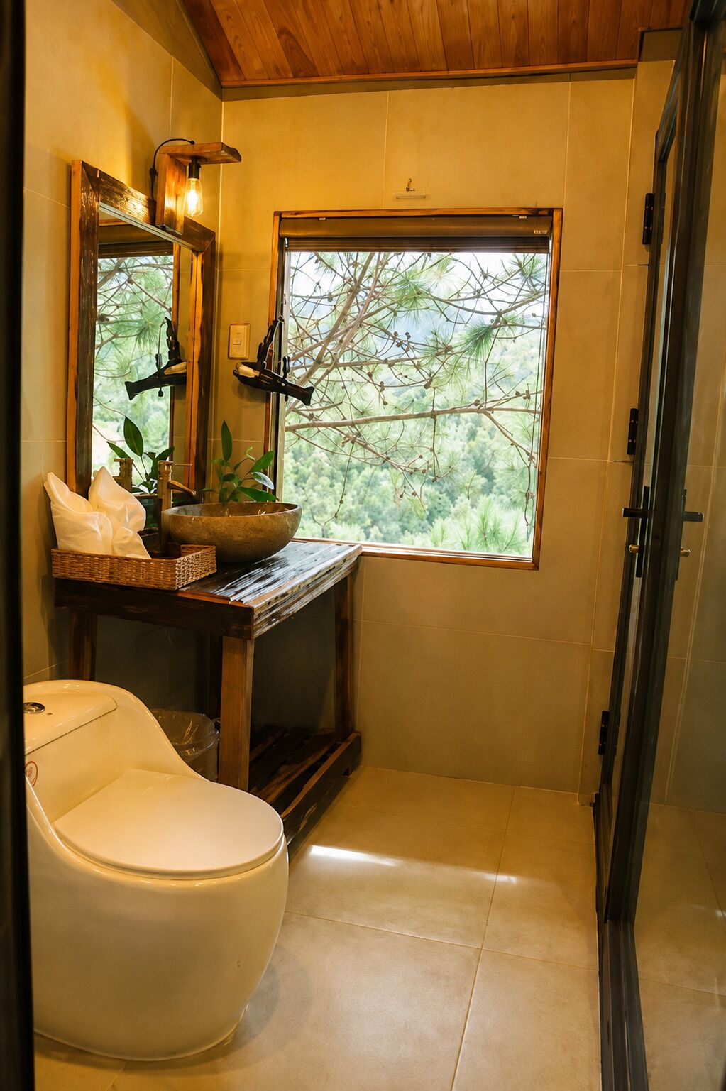 A bathroom with a toilet, a sink with a wooden countertop, a mirror, and a window with a view of trees.