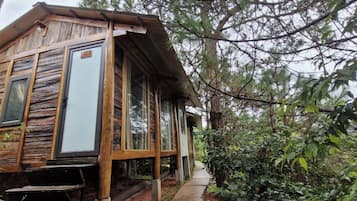 Una cabaña rústica con fachada de madera, ventanas amplias y un porche.
