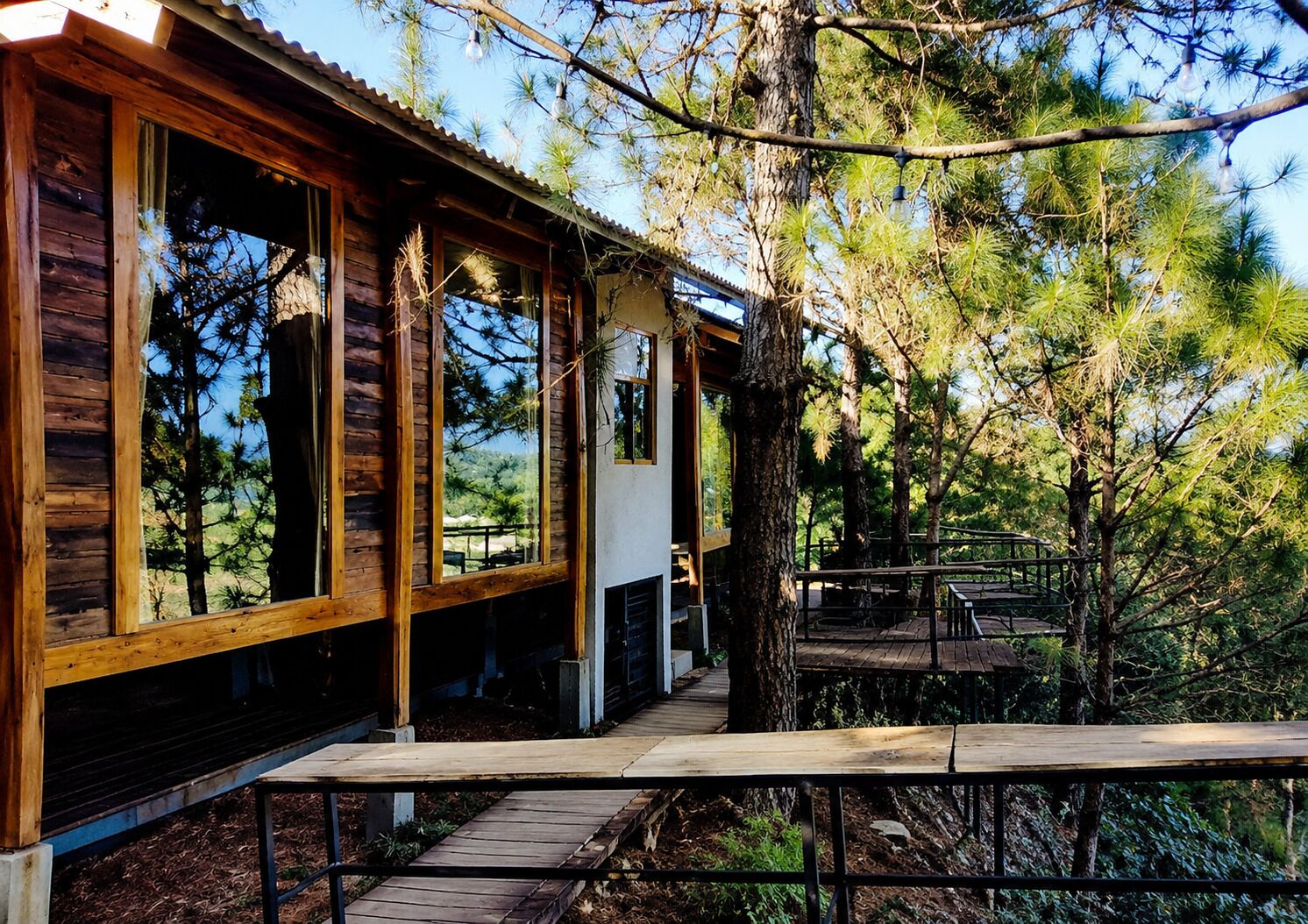 A wooden cabin with large windows, a porch, and a view of surrounding trees.