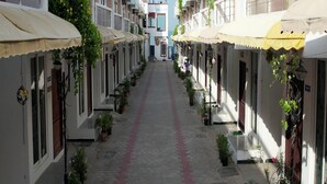A narrow street lined with two-story buildings, each with a flat roof and a small awning. The street is paved with hexagonal tiles and has a red line running down the center. - Kovalam Studio Villa (Tirupporur)