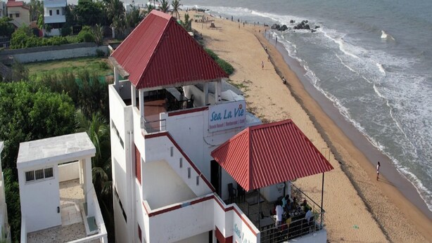 A beachside building with a red roof, a sign reading "Sea La Vie Beach Resort & Restaurant," and a view of the ocean. - Kovalam Studio Villa (Tirupporur)