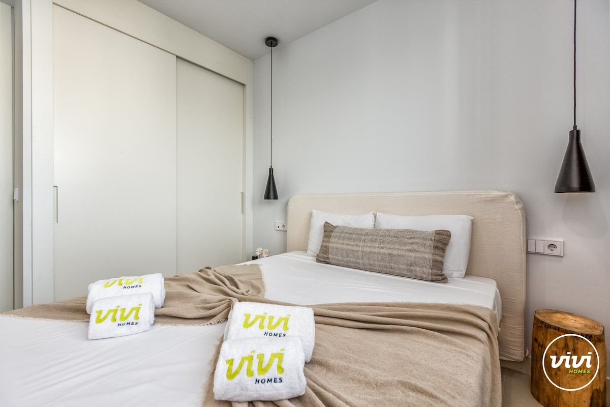 Une chambre d’hôtel avec un lit, une table de chevet, une lampe et une armoire.
