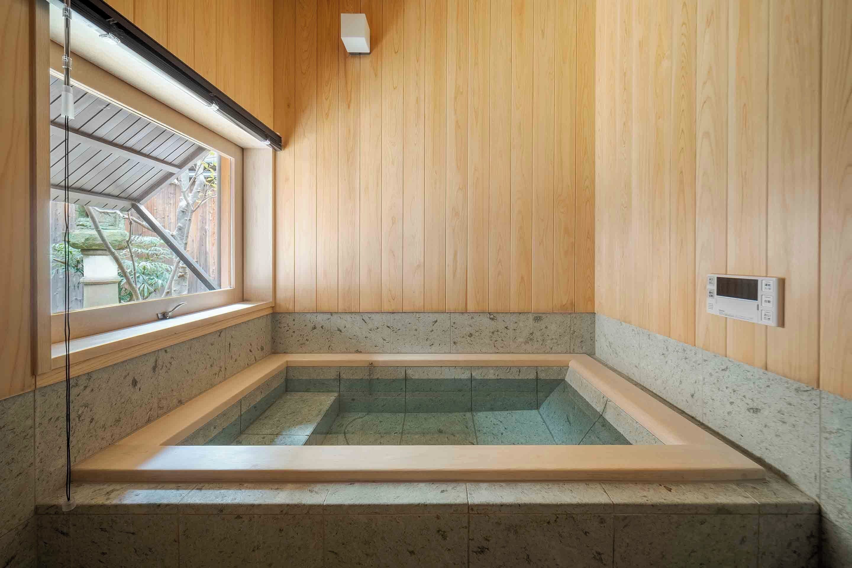 A modern bathroom with a wooden interior, a built-in bathtub, and a window providing natural light.