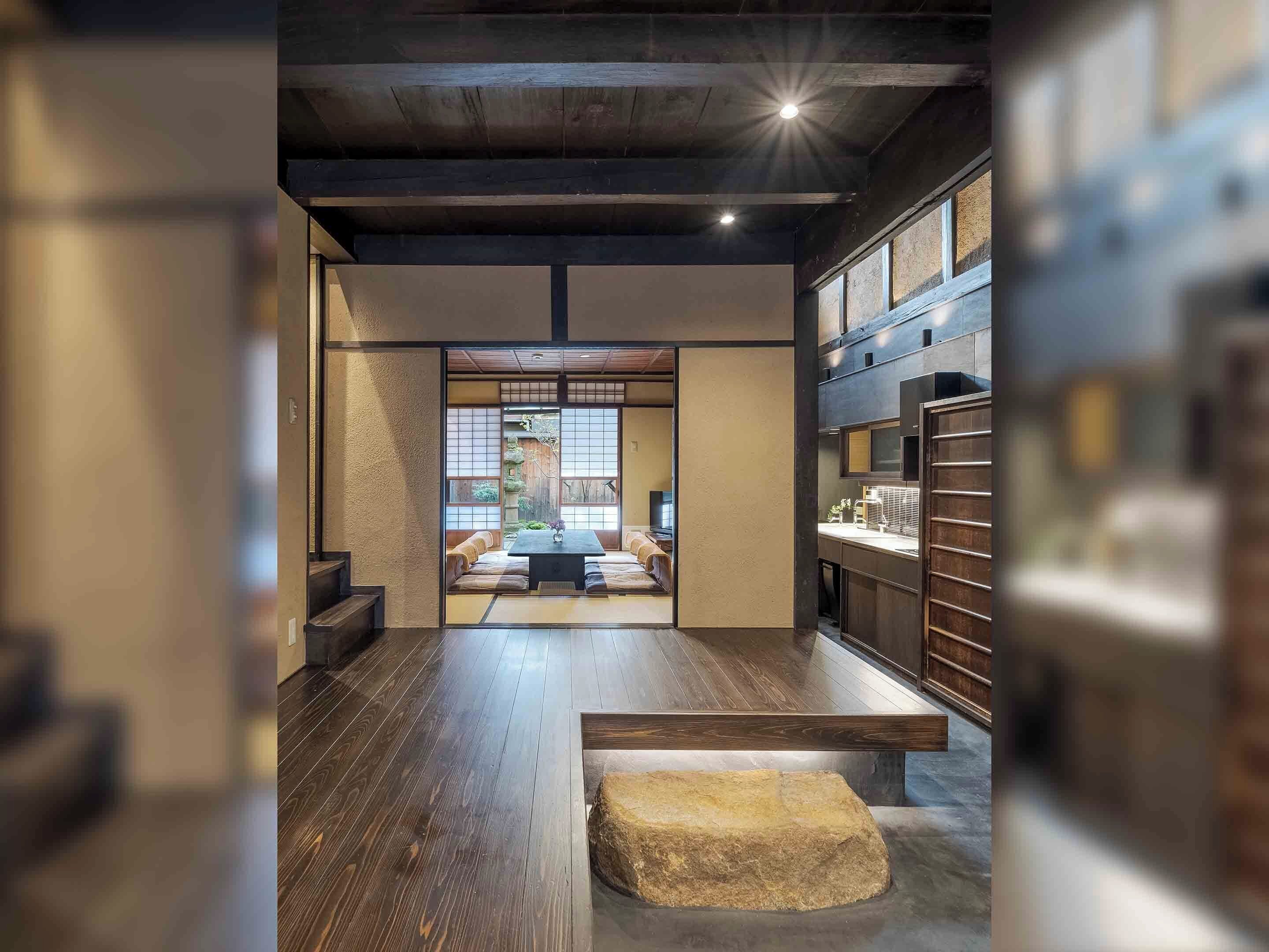 A traditional Japanese interior with tatami flooring, a low wooden table, and a stone bench.