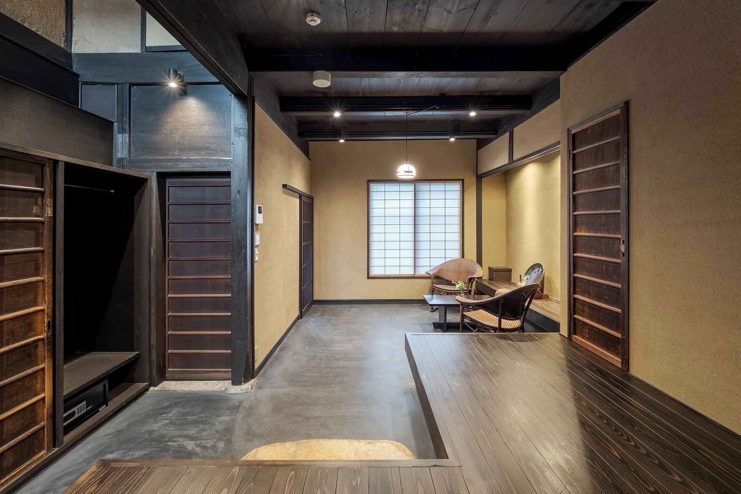 Un couloir étroit au plancher en bois, un tatami au centre et une porte coulissante japonaise traditionnelle sur le côté gauche.