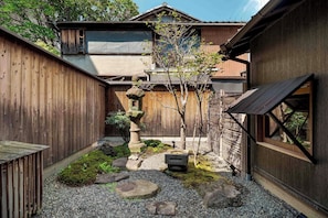 Una casa tradicional japonesa con jardín, vallas de madera y un farol de piedra.