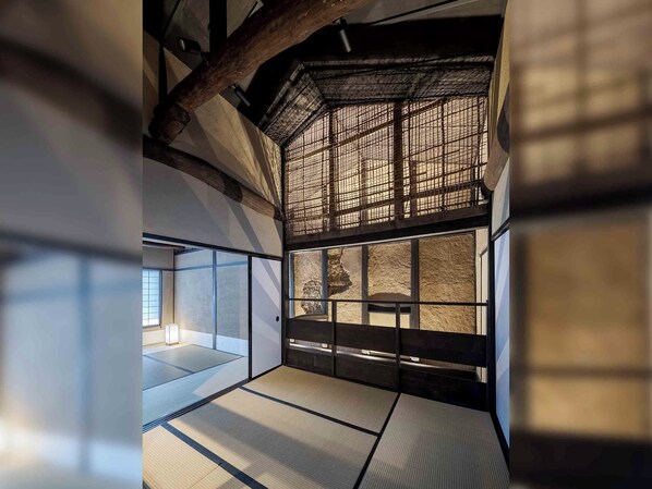 Una habitación japonesa tradicional con suelo de tatami, un biombio shoji y una chimenea de piedra.
