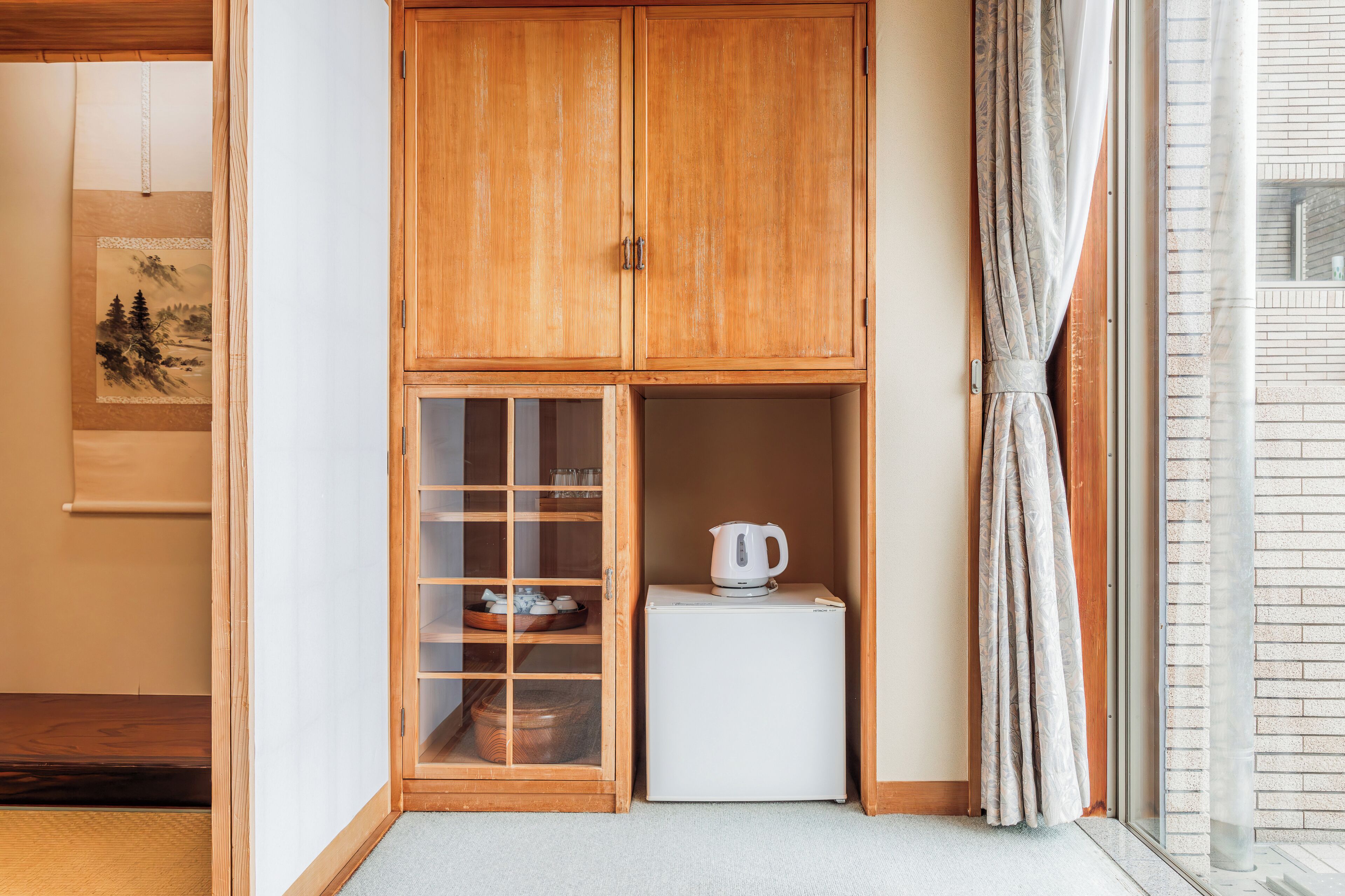 A traditional Japanese room with a wooden cabinet, a small refrigerator, and a sliding door.