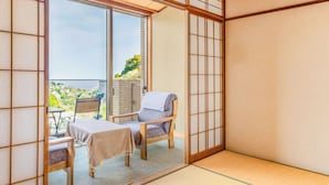 Una tradizionale stanza giapponese con pavimento in tatami, una porta scorrevole, un tavolo coperto da una tovaglia e una sedia.