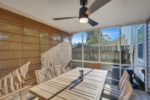 Enjoy a patio with a table, chairs, and a ceiling fan, offering a view of the backyard through large windows.