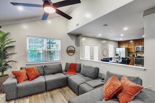 Relax in this stylish living room with a sofa, ceiling fan, and large window.