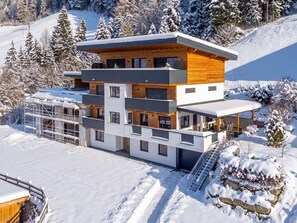 A modern multi-story building with a ski slope in the background. - Modern holiday flat with stunning views (Hart im Zillertal)