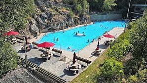 Una amplia piscina al aire libre rodeada de terreno rocoso y vegetación.
