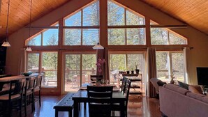 Una habitación amplia con techo alto, ventanas grandes, zona de comedor y espacio para sentarse.