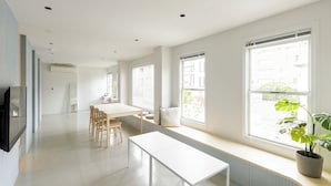A modern, well-lit room with a large window, a bench, and a dining table with chairs. - HOTEL ReONcE Shibuya (Tokyo)