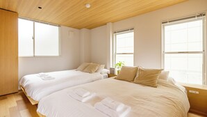 A hotel room with two beds, wooden flooring, large windows, and a ceiling light. - HOTEL ReONcE Shibuya (Tokyo)