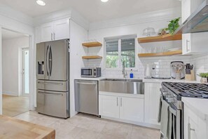 Een koelkast, een kookplaat, een vaatwasser, kookgerei, borden en bestek