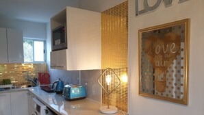 A modern kitchen with a built-in washing machine, a microwave, and a toaster on the counter. - CUTE, COMFY, AFFORDABLE STUDIO 23 +CARPARK  (Auckland)