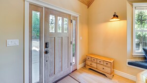 Une porte en bois avec un panneau de verre, un banc en bois et un luminaire fixé au mur.