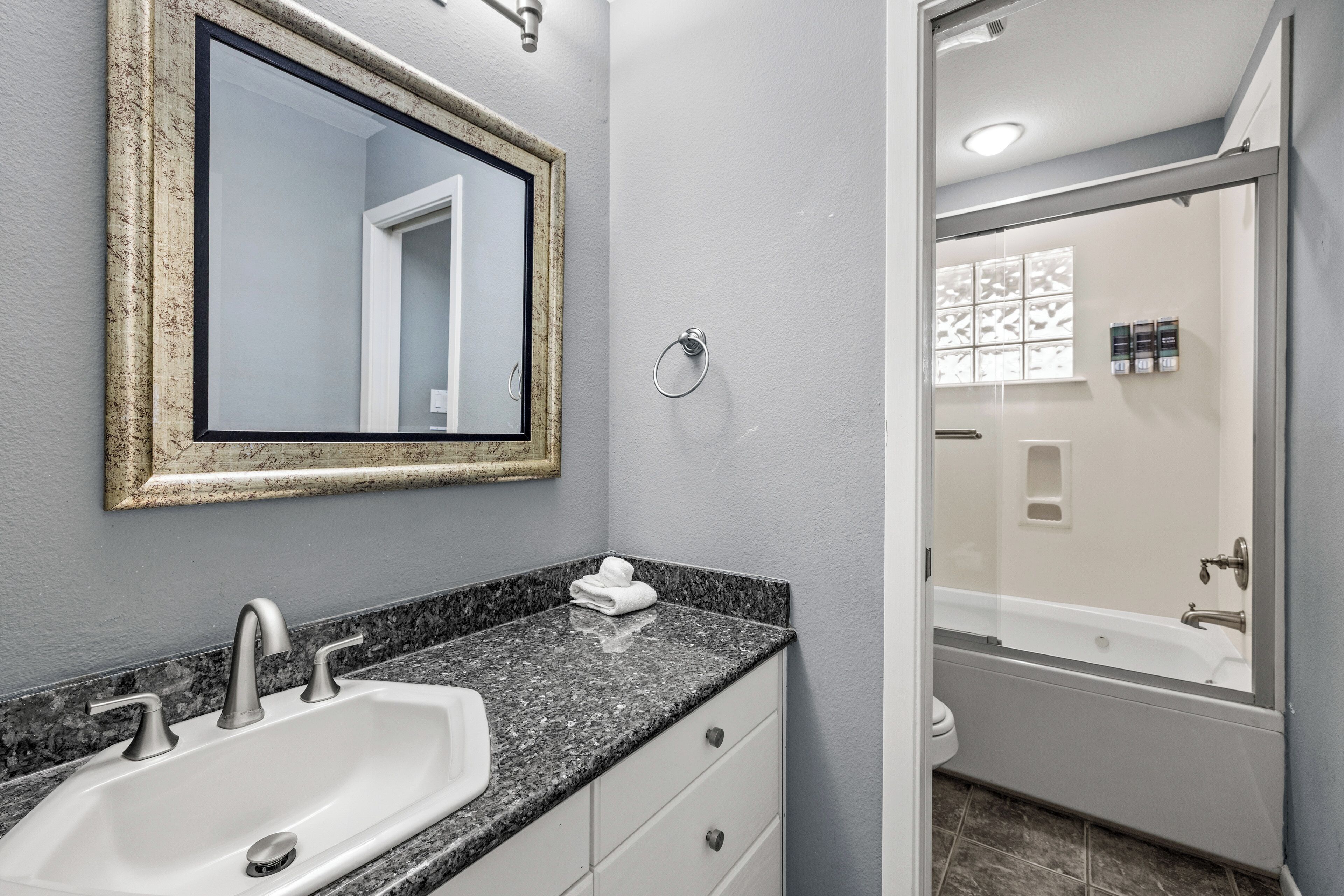 A bathroom with a sink, mirror, and a shower area.