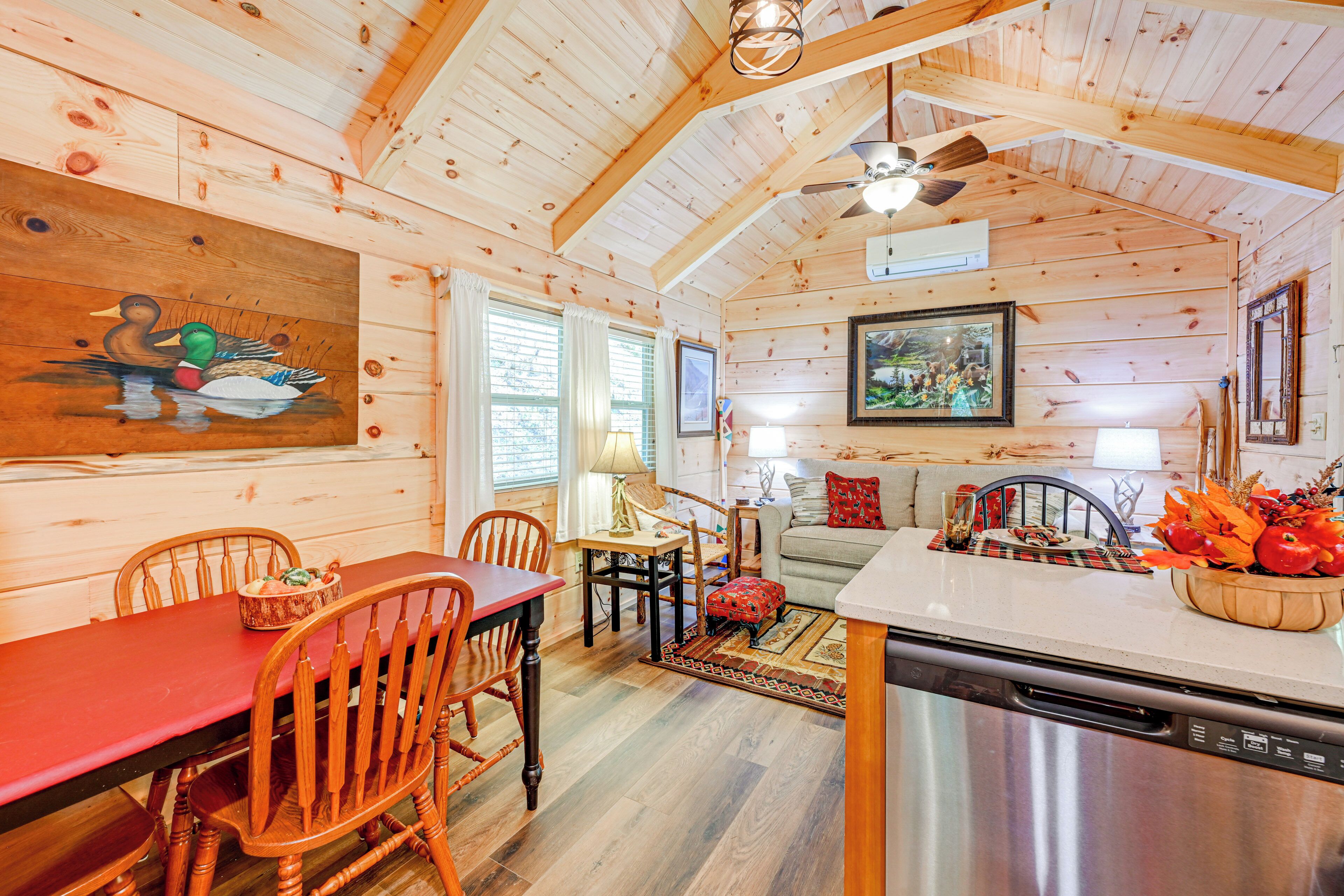 A wooden cabin interior with a dining area, kitchen, and living space.