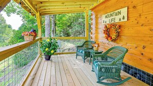 Eine Holzterrasse mit Korbstühlen und einem Tisch, umgeben von einem Metallgeländer. Ein Schild an der Wand zeigt den Schriftzug „MOUNTAIN LIFE“.