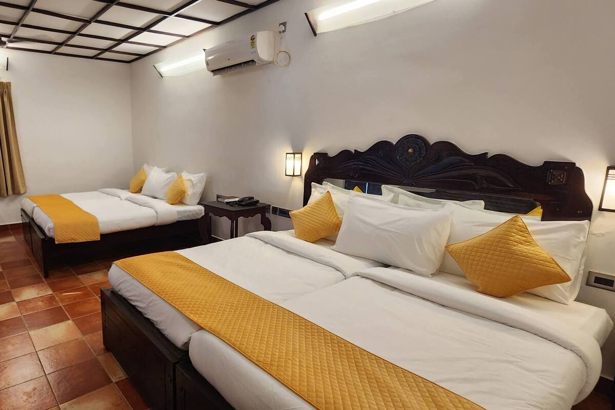 Una habitación de hotel con dos camas, una silla, una mesa y un ventilador de techo.
