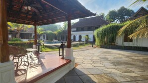 Ett takförsett utomhusområde med sittplatser, och en pool syns i bakgrunden.