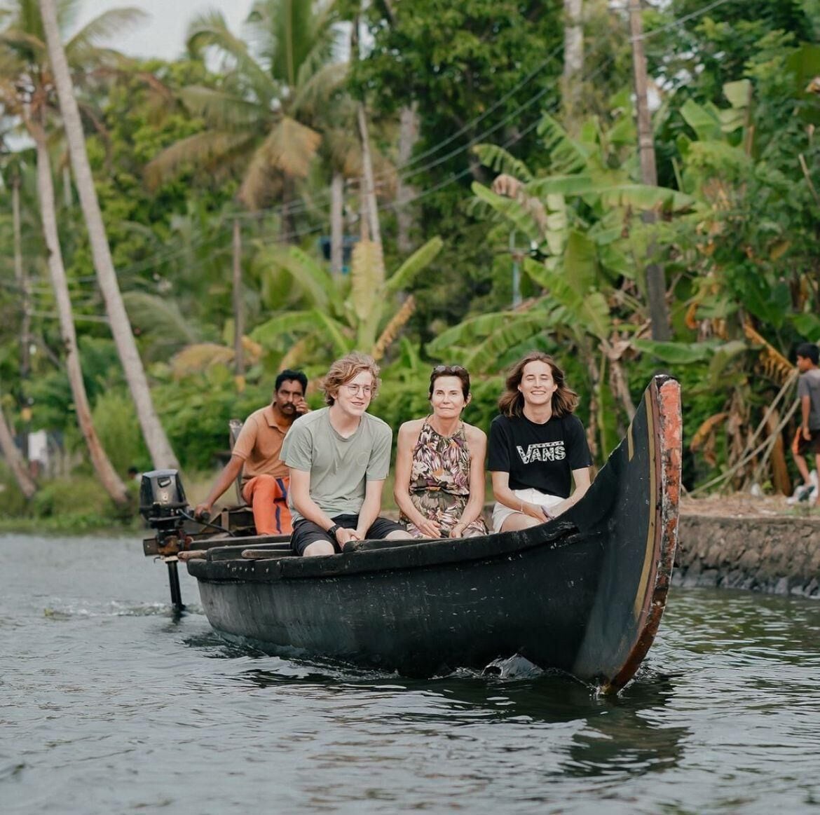 A group of people in a small boat on a river surrounded by lush greenery.
