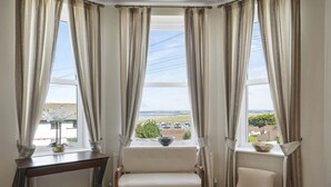 A room with a large window, two chairs, a small table, and a bowl on the windowsill. - Modern Apartment, Private Parking, Walk to Beach! (Westward Ho)