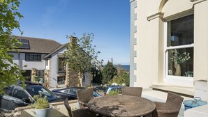 A patio with wicker furniture, a pool, and a view of the sea. - Modern Apartment, Private Parking, Walk to Beach! (Westward Ho)