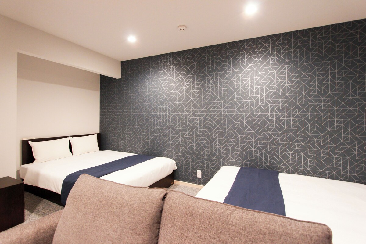 A hotel room with two beds, a dark patterned wall, and a modern design.
