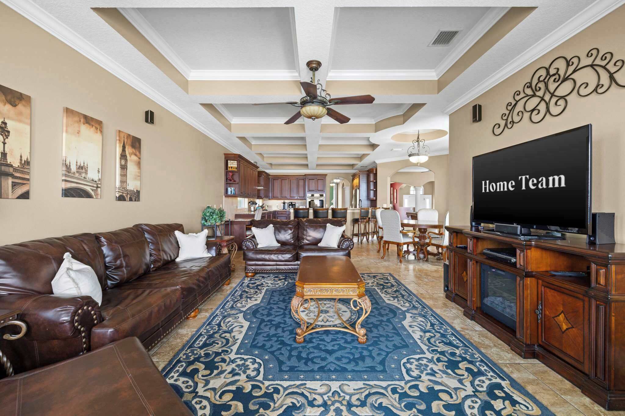 A spacious living room with a brown leather sofa, a wooden coffee table, and a large flat-screen TV.