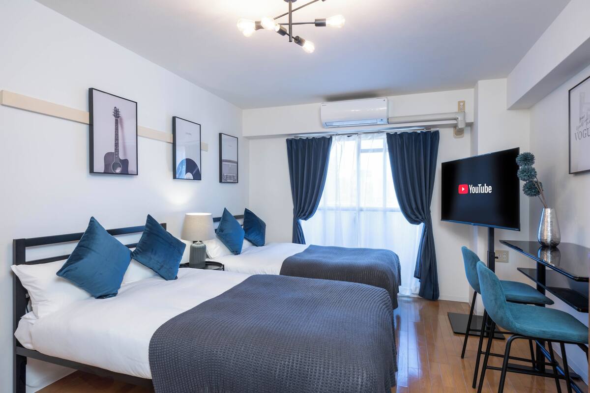 A hotel room with two beds, a TV, a desk, and a chair.
