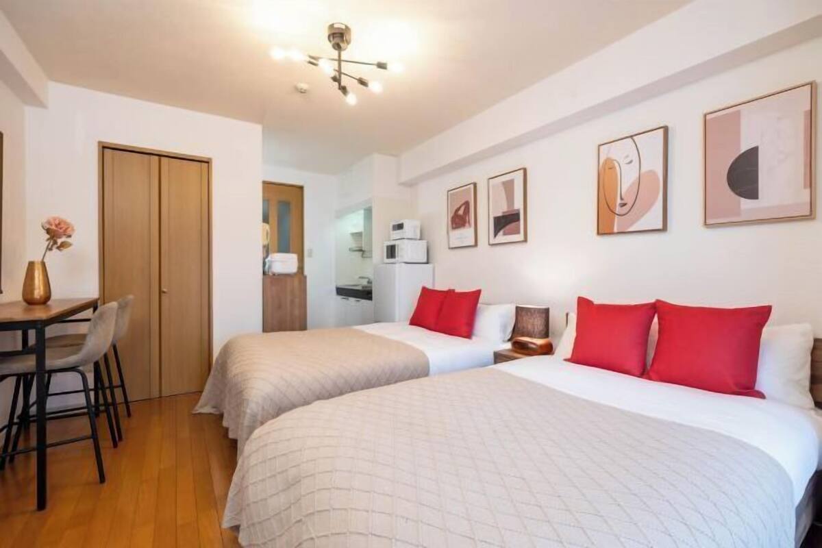 A hotel room with two beds, a desk, a chair, and artwork on the walls.