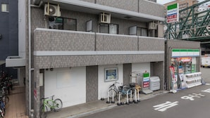 Un immeuble à plusieurs étages doté de balcons, de climatiseurs et d’un magasin de proximité FamilyMart au rez-de-chaussée.