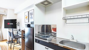 Une cuisine moderne équipée d’une cuisinière intégrée, d’un évier et d’un téléviseur à écran plat fixé au mur.