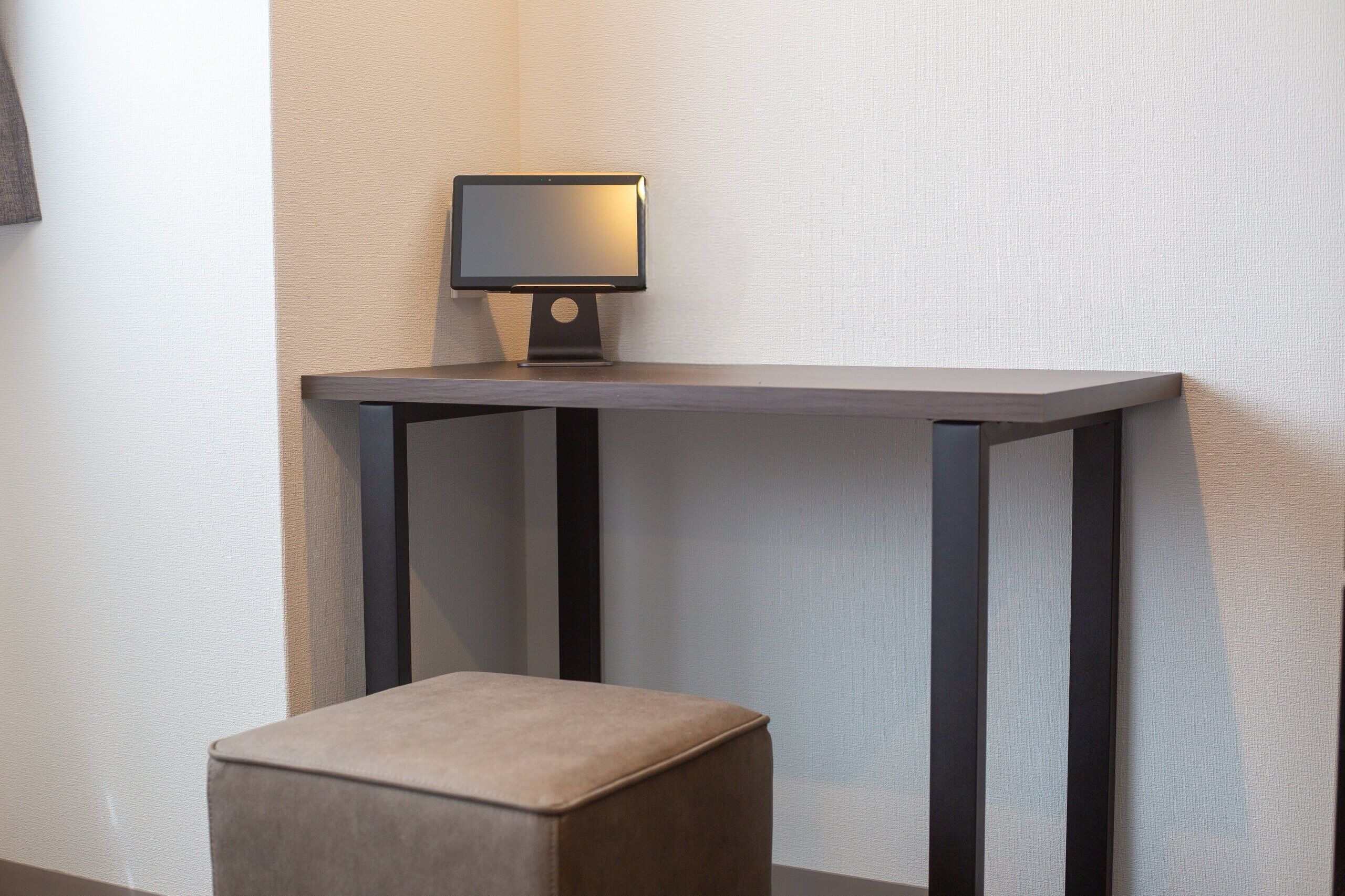 Una habitación moderna con una pequeña mesa y un taburete acolchado.