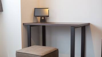 Una habitación moderna con una pequeña mesa y un taburete acolchado.