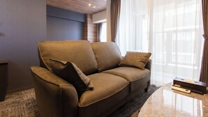 Un salon moderne avec un canapé en cuir marron, une télécommande et une boîte posée sur une table basse en marbre.