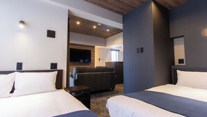 Une chambre d’hôtel avec deux lits, un canapé, une télévision et un plafond en bois.