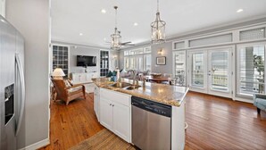 A spacious kitchen with granite countertops, stainless steel appliances, and pendant lighting.