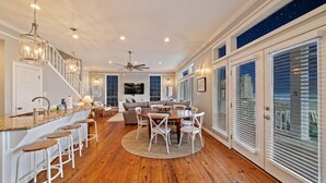 A spacious kitchen with a central island, bar stools, and a dining area with a round table and chairs.