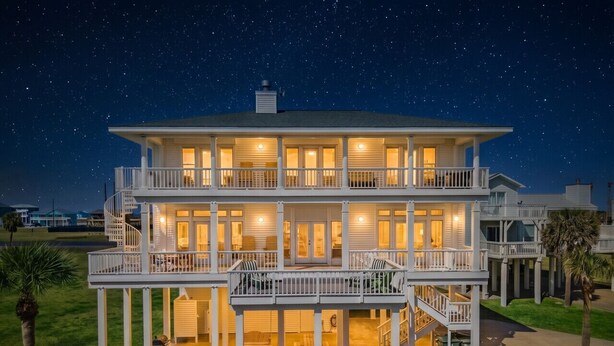 A two-story house with a balcony, a patio with outdoor furniture, and a clear night sky.