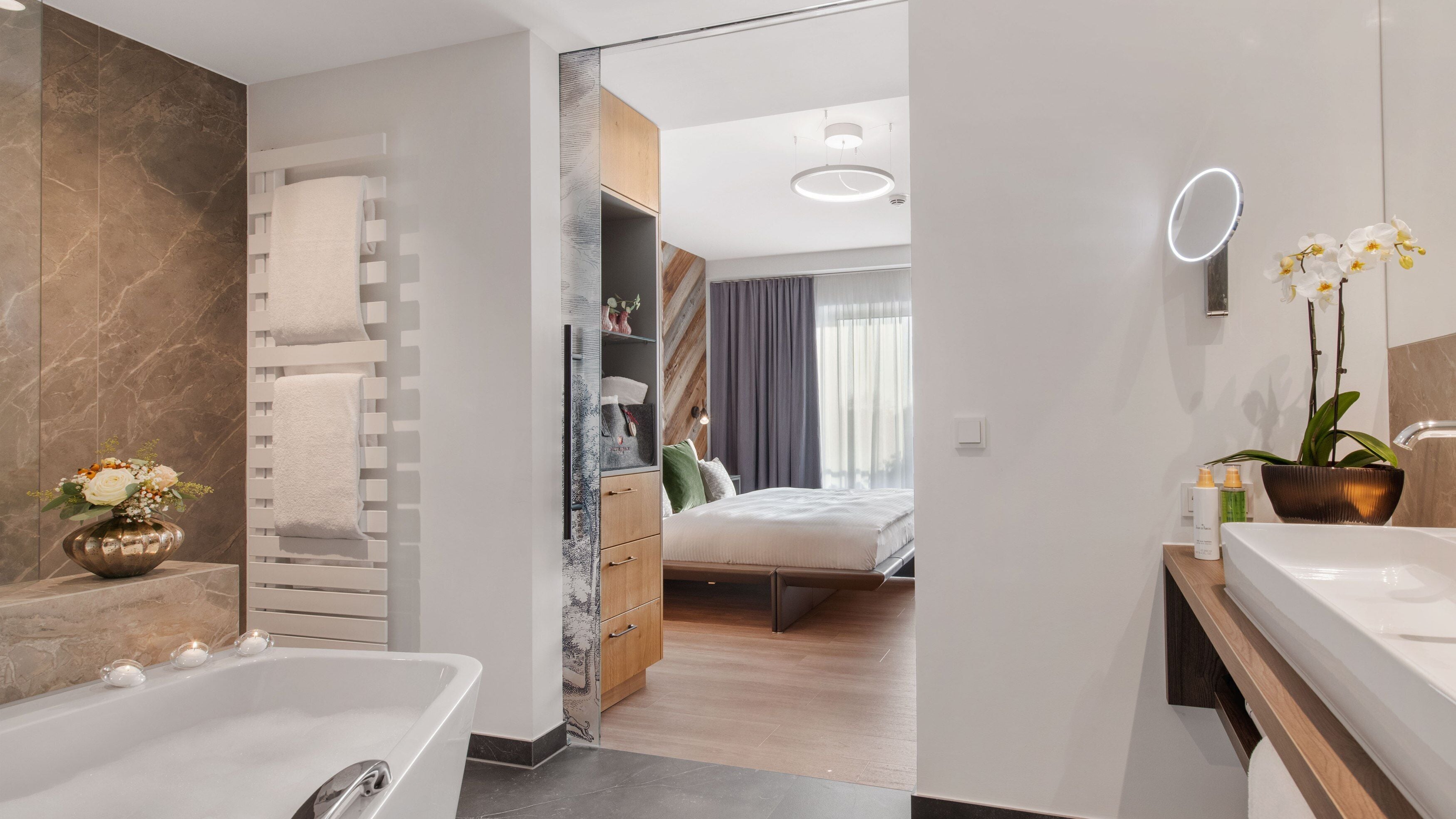 A modern bathroom with a bathtub, a vanity with a mirror, and a potted orchid.
