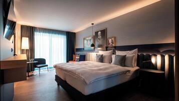 Una habitación de hotel moderna con una cama grande, mesitas de noche, un escritorio y una silla.